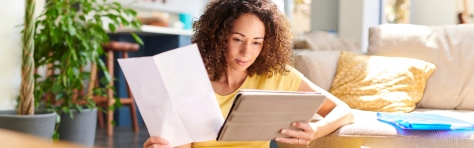 Woman looking at paper and Ipad checking her finances