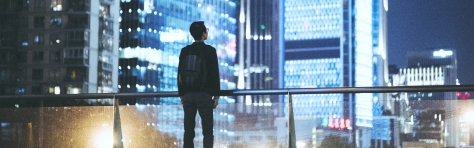 man standing in modern city at night, financial district, audit, professional services, skyline, office buildings