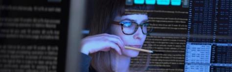 Woman studying through a see through computer screen & contemplating. Data technology analysing. 