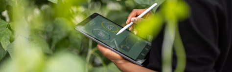 An image of a woman updating plants growth on a digital tablet.