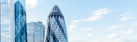 City of London skyline. Gherkin building in European city, financial district, offices, blue building with clear sky background, United Kingdom, UK, England, English.