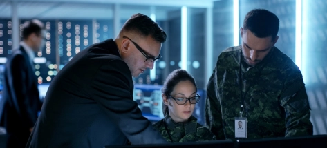 Three government/military officers standing round computer