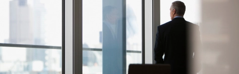 An image of a businessman looking out of a window in his office. 