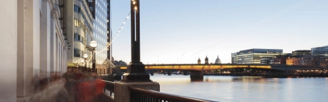 Blurred motion of people walking along the bank of River Thames with view of London Bridge and St Paul's Cathedral behind