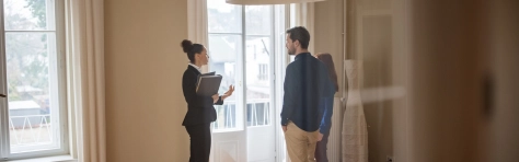 Image of a businesswoman standing in a flat with a man and woman 